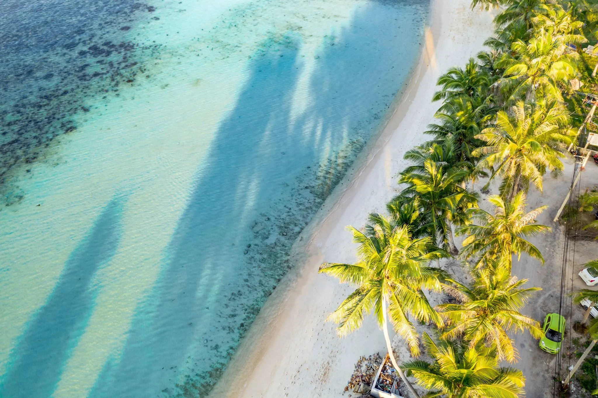 Aerial view of white sand beach meeting crystal blue waters along the southern coast of Koh Samui