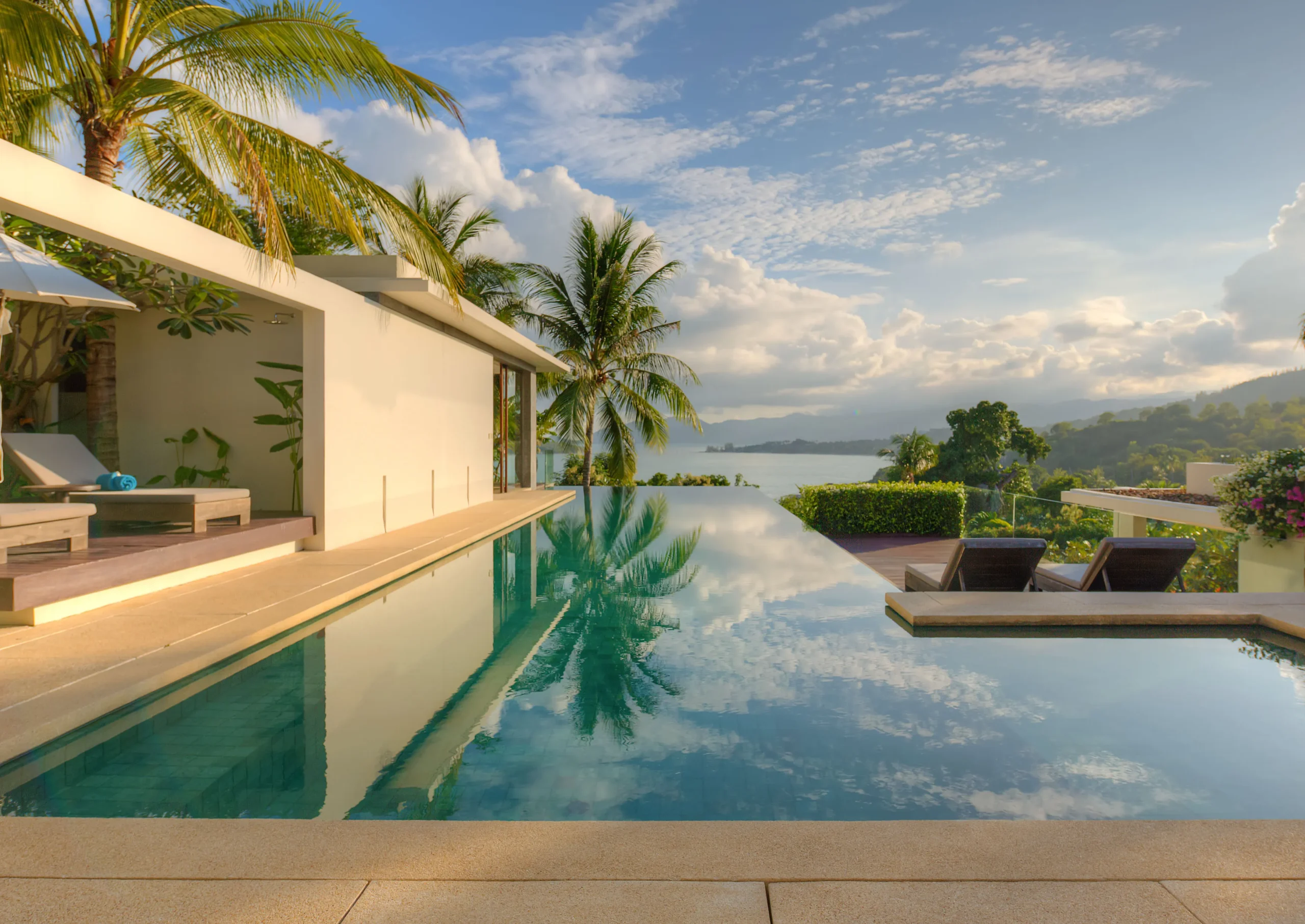 Low-angle infinity pool view toward villa facade, open sea and headland, Koh Samui